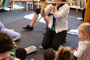 Éveil musical à la médiathèque Médiasud. Une personne joue d'un instrument de musique devant un public d'enfants et d'adultes. 